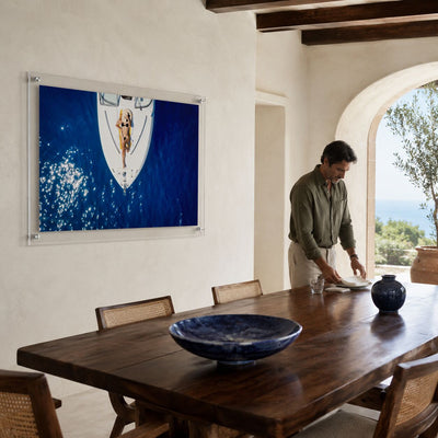 Sun Deck Society wall art in a dining room with a man standing nearby