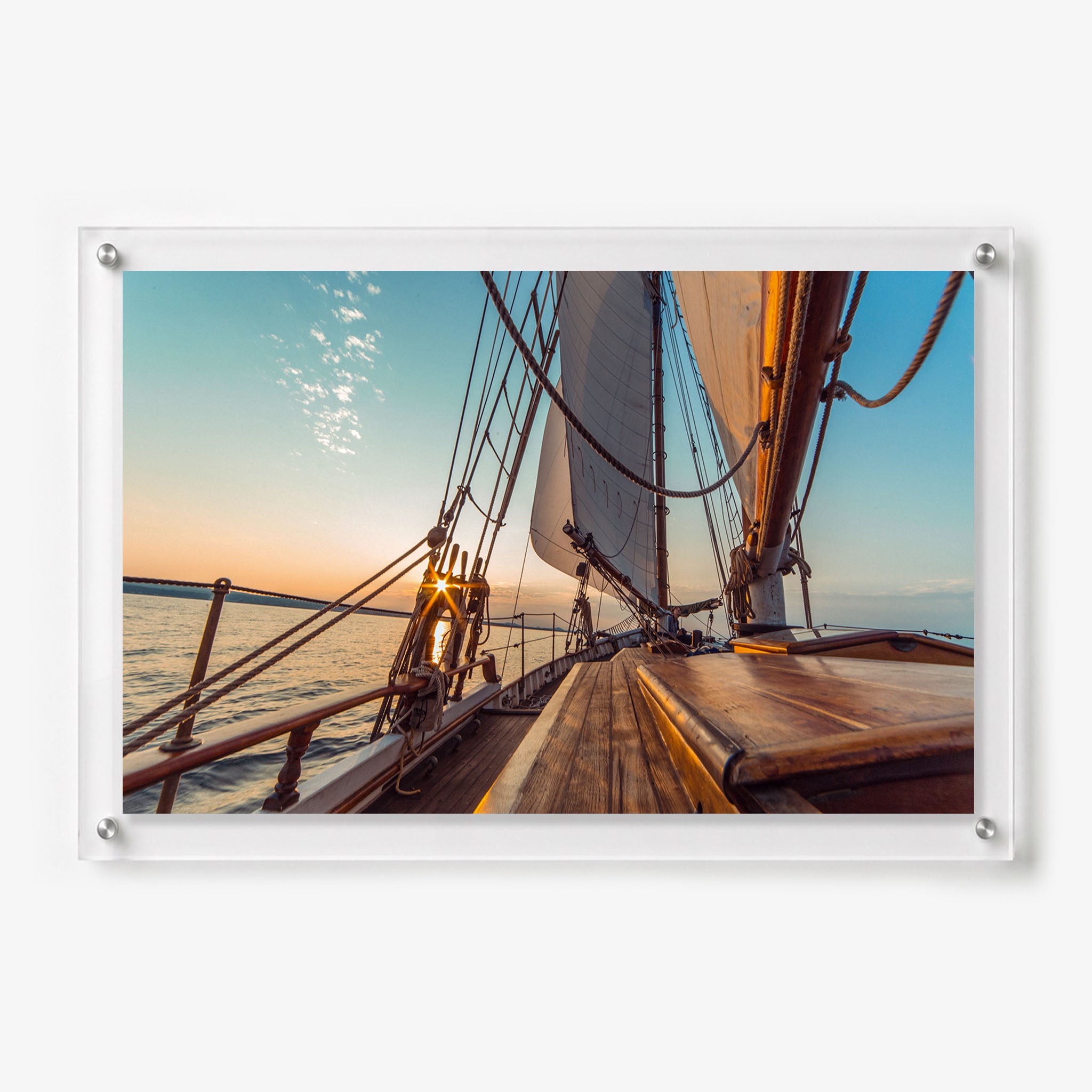 Acrylic wall art featuring the wooden deck and raised sails of a classic sailboat at sunset