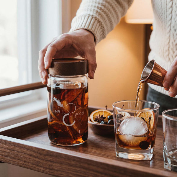 Person pouring an old fashioned cocktail beside a jar