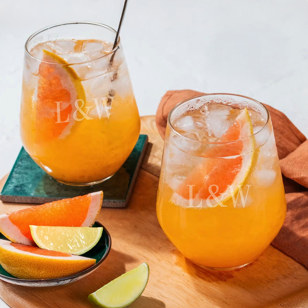 2 stemless wine glasses with orange cocktails and garnish.