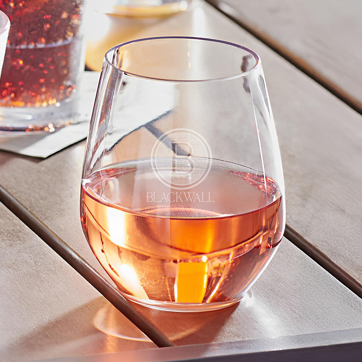 Close-up of the stemless wine glass with engraved initial and name.