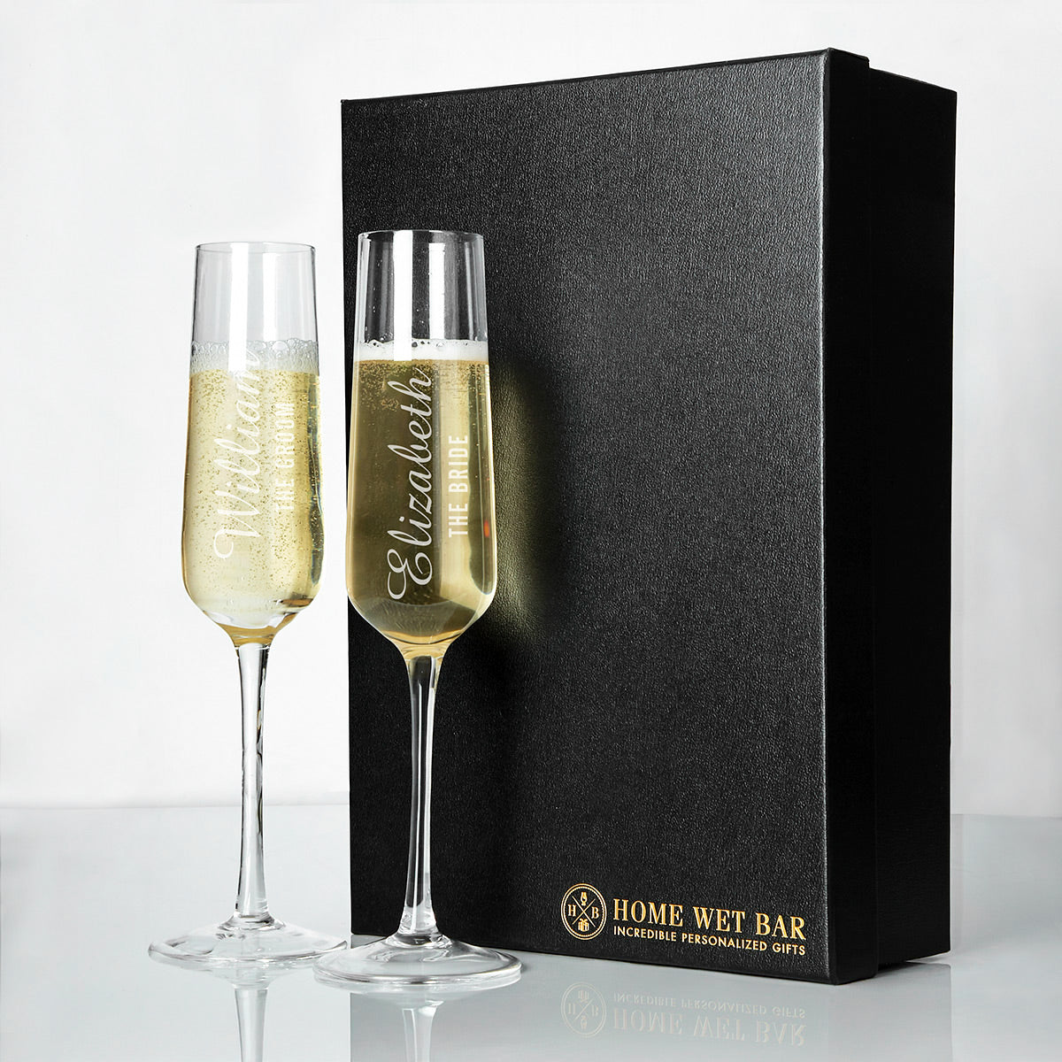 two customized champagne glasses sitting on a table next to a black luxury box