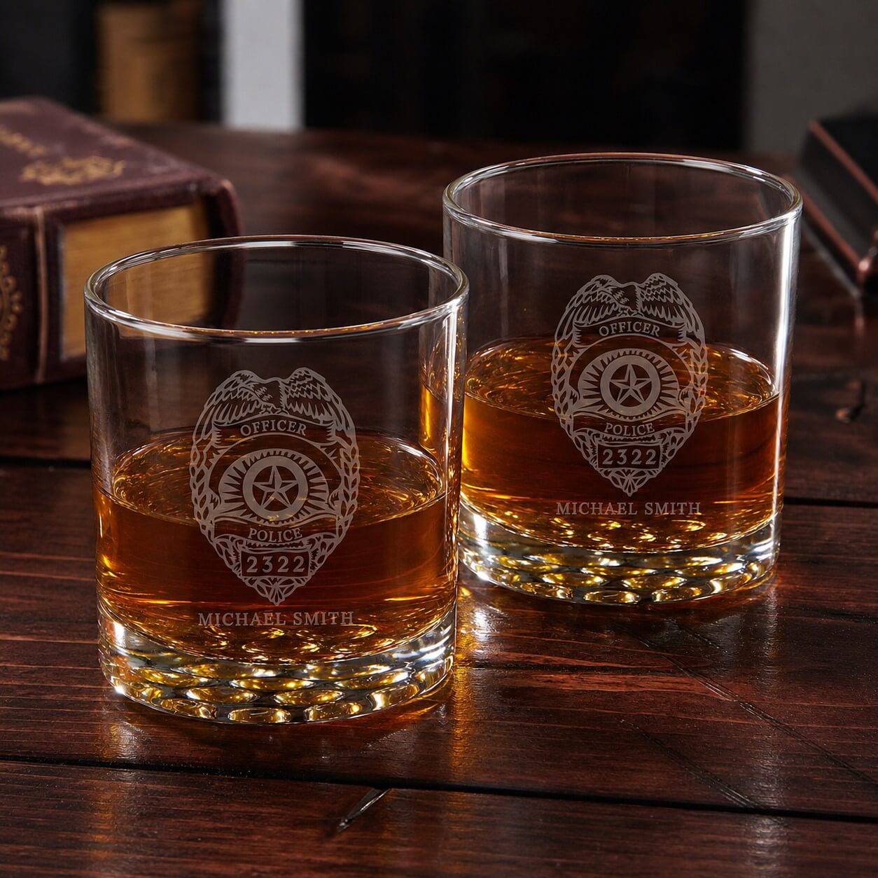 Two glasses with police badge engraving filled with a amber liquid on a wooden surface.