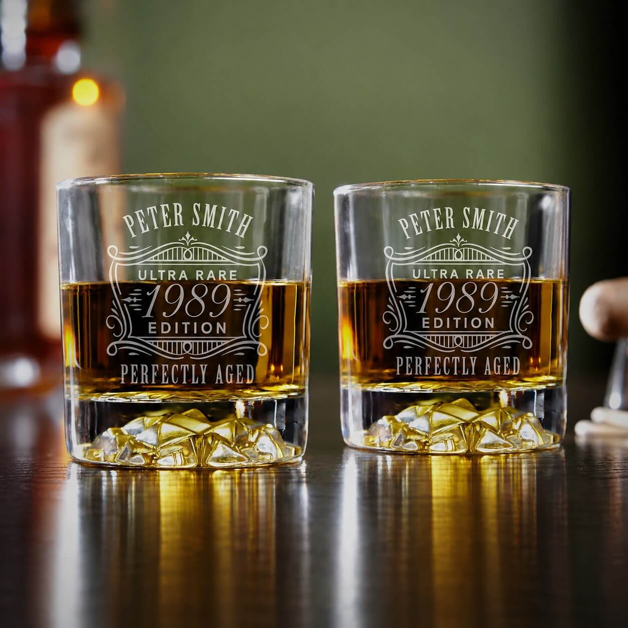 Two whiskey glasses with engraved text on a wooden surface
