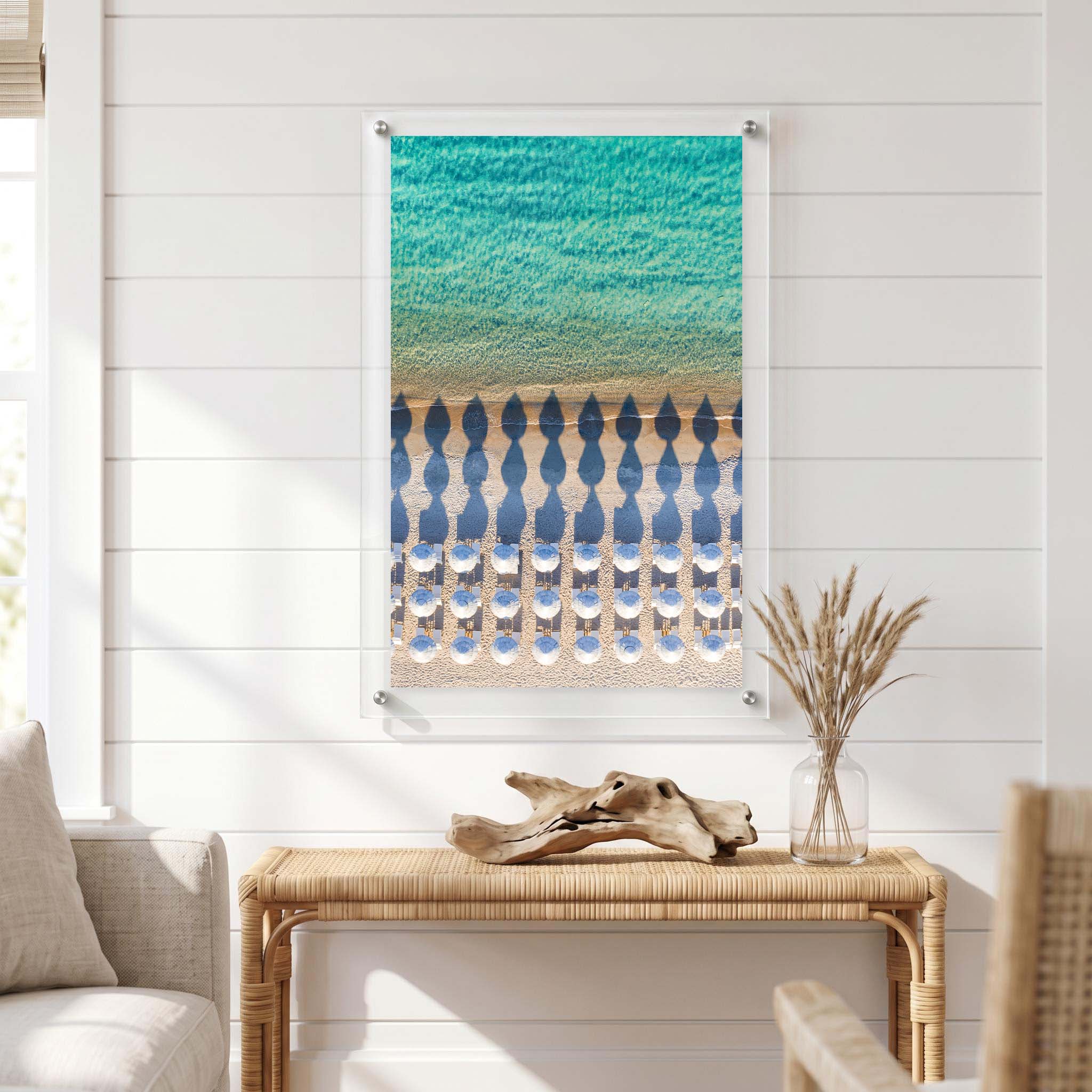 Coastal acrylic wall art print showing an organized beach setup displayed in a bright living room