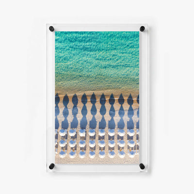 Overhead beach scene with white umbrellas, lounge chairs, golden sand, and gentle waves