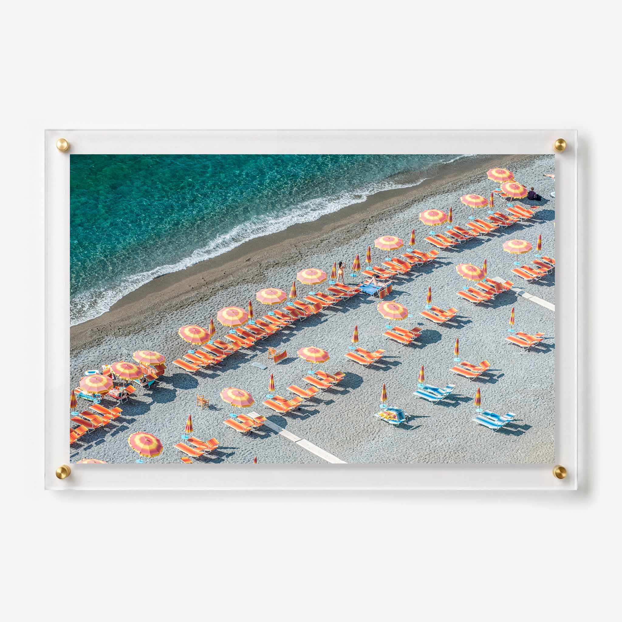 Aerial view of orange beach umbrellas and lounge chairs beside clear turquoise water