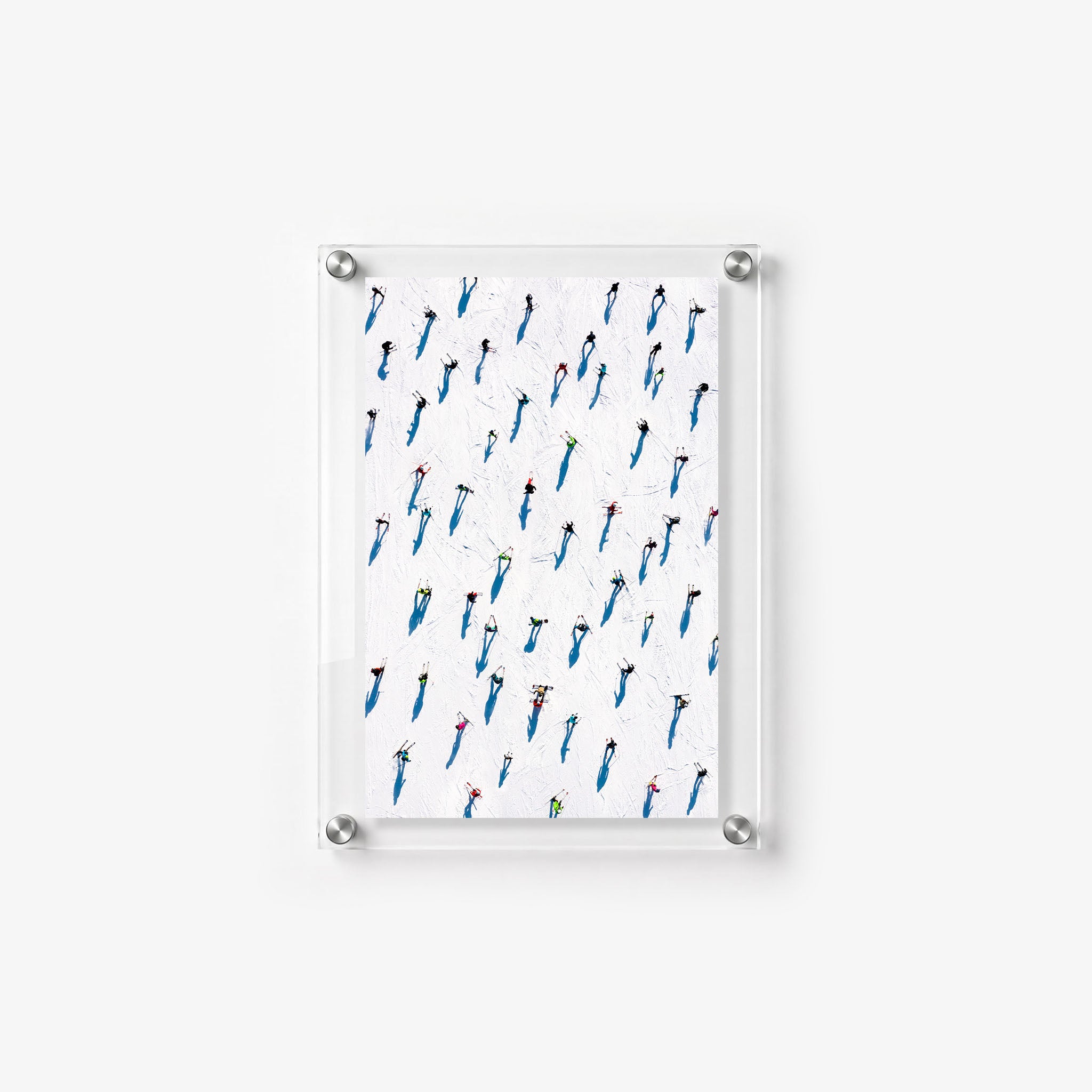 Vertical winter wall print showing small skiers and vivid blue shadows across a white ski field