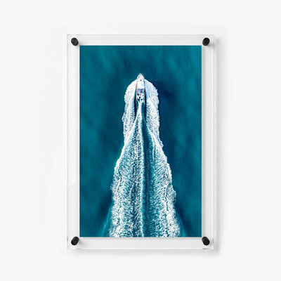 Aerial ocean scene with a motorboat creating symmetrical white trails across dark blue water