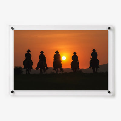 Acrylic wall art featuring five cowboys on horseback silhouetted against a glowing orange sunset