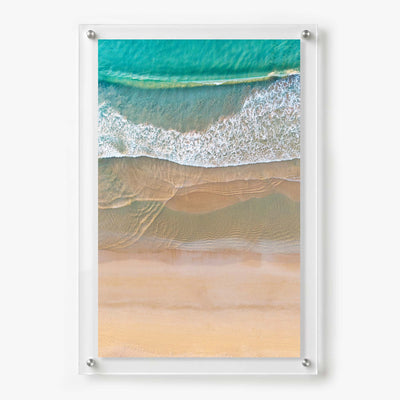 Acrylic wall art featuring an aerial view of turquoise waves washing onto a soft sandy beach