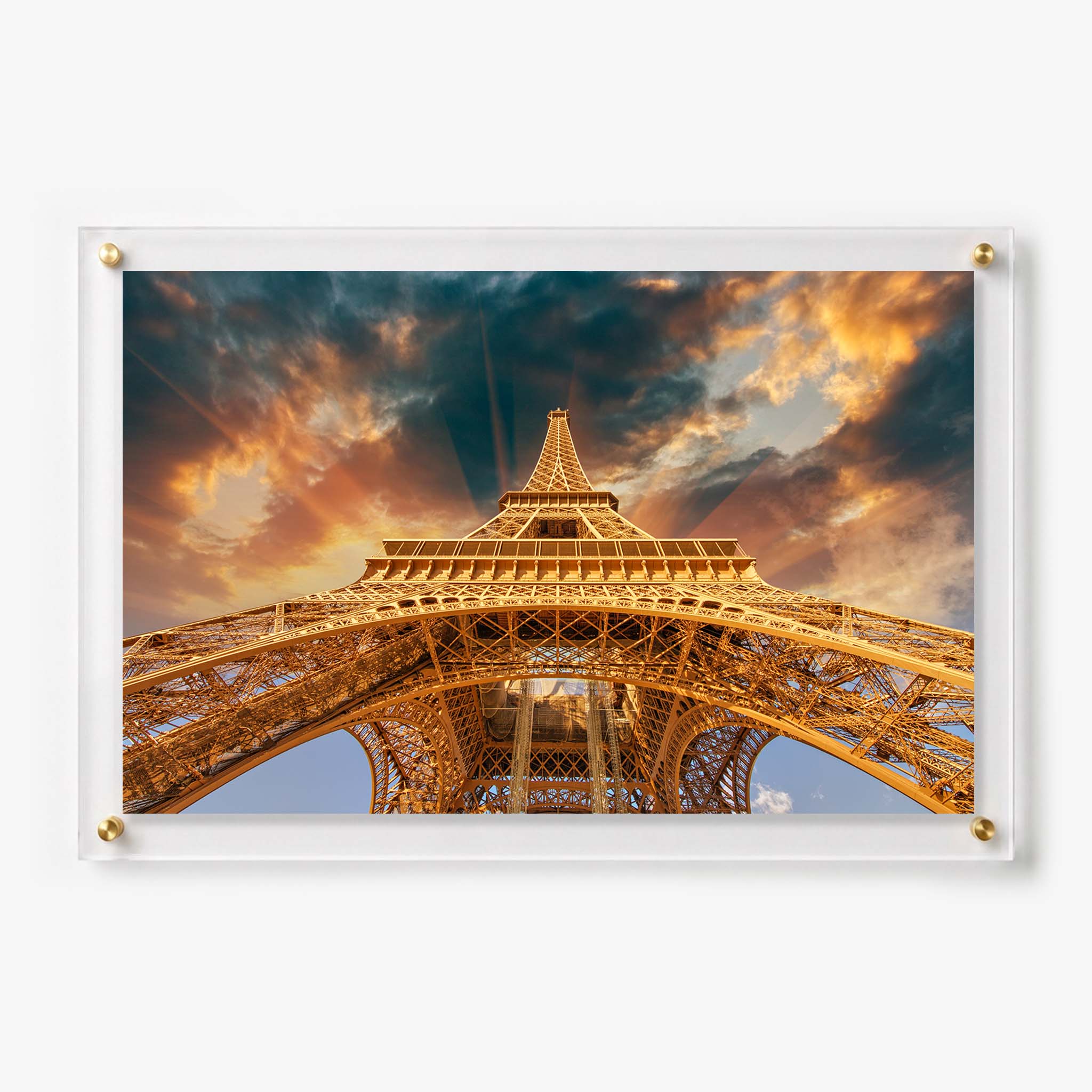 Low angle view of the Eiffel Tower glowing beneath dramatic golden clouds