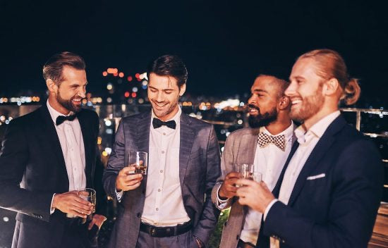 Four men in suits drinking whiskey outside