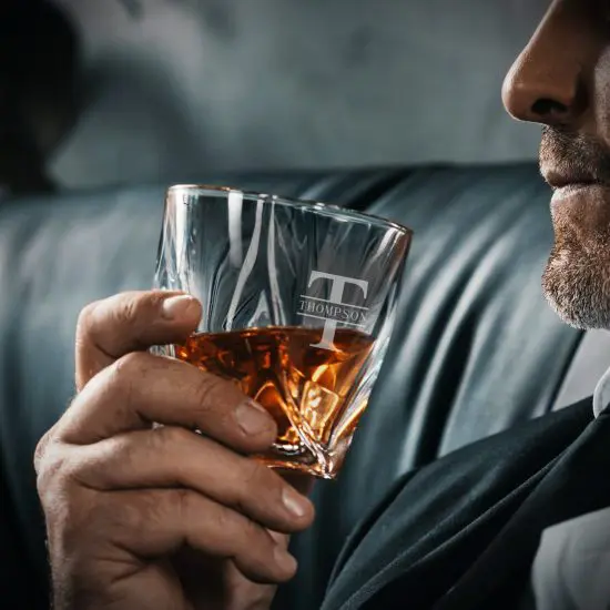 man sipping bourbon on leather couch 