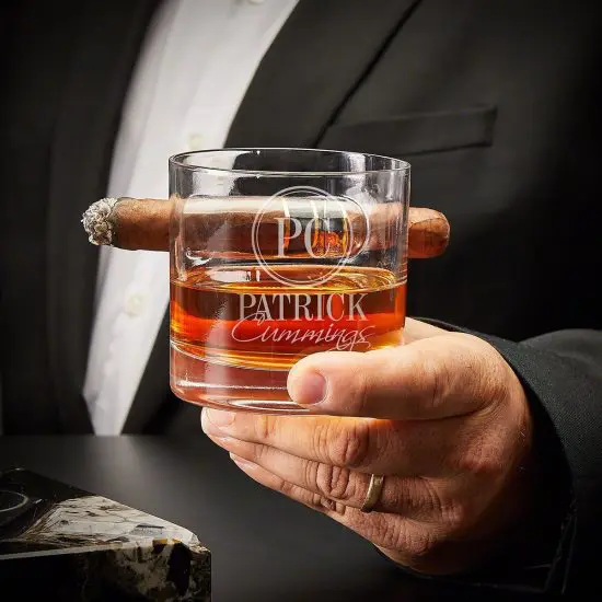 man with cigar holding whiskey glass