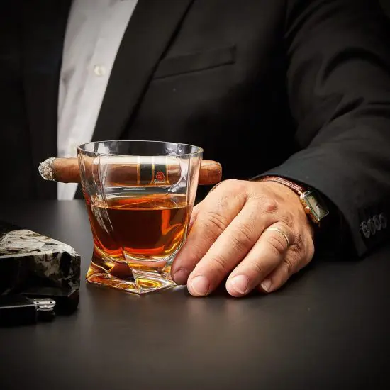 man in suit with cigar and bourbon glass