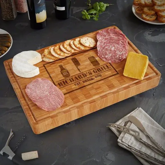 Bamboo cutting board with meat, cheese, and crackers on top
