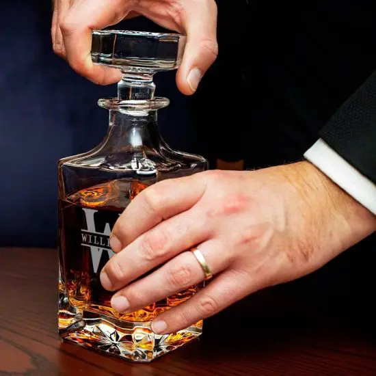 Man in suit removing the top of a whiskey decanter