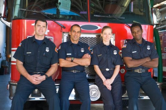 Four firefighters sitting on a fire truck