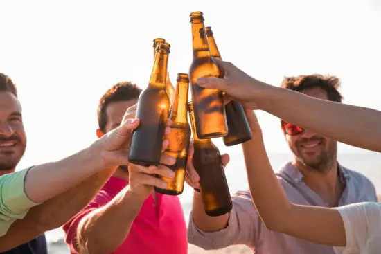 Men cheers with beer bottles