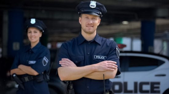 Two police officers standing in front of a squad car