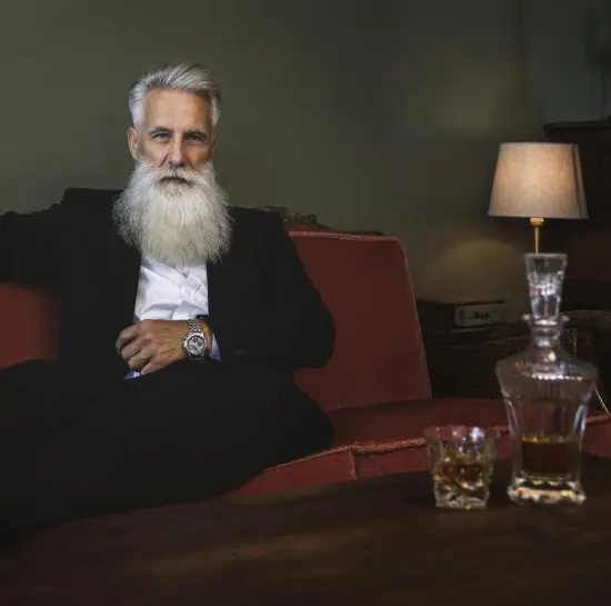 Bearded man sitting on couch near decanter set