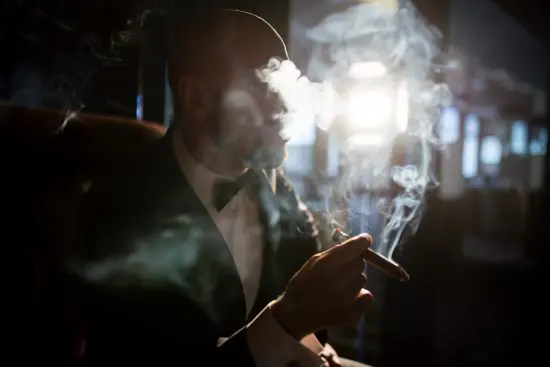 Man in suit surrounded by cigar smoke