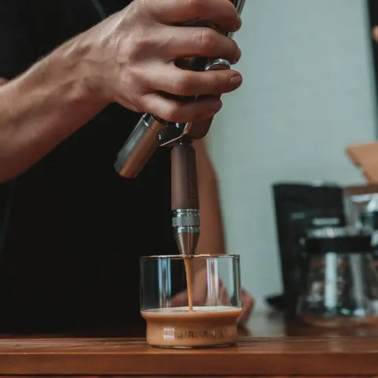 Man infusing a cup of coffee with nitrogen using NitroPress