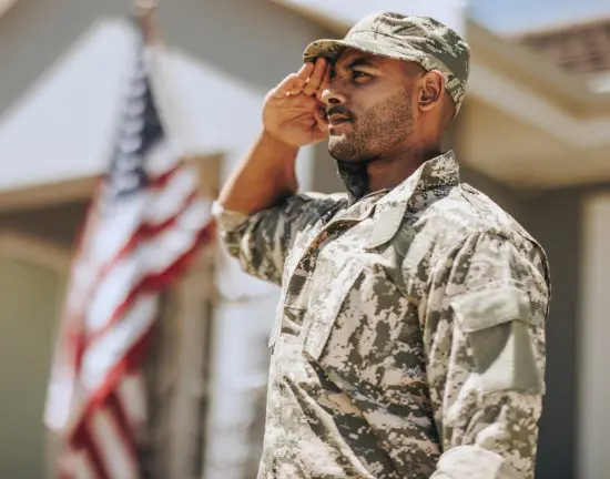 Man in Army soldier outfit saluting near American flag