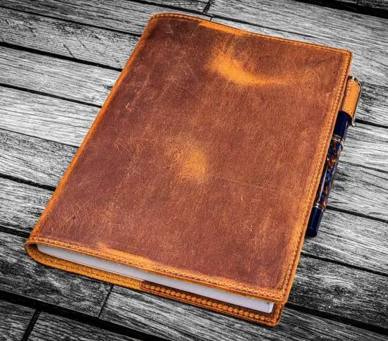 Leather notebook cover with notebook and pen on wood table