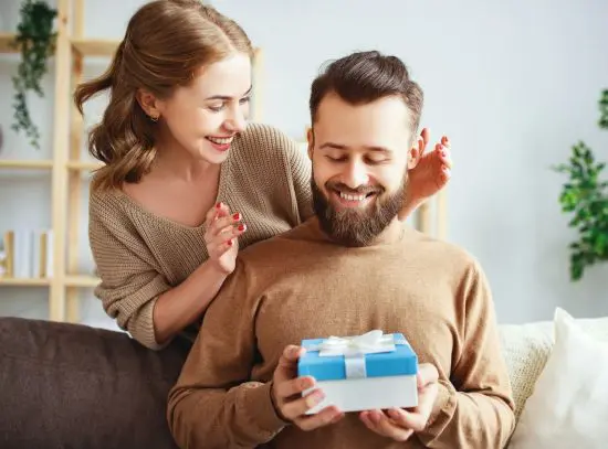 Man receiving badass gift for guys from woman on couch