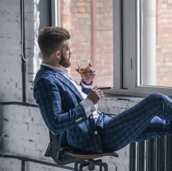 Man staring out of window with whiskey glass in hand