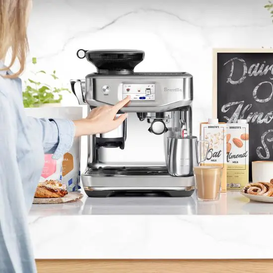 Woman using a Breville espresso machine in kitchen