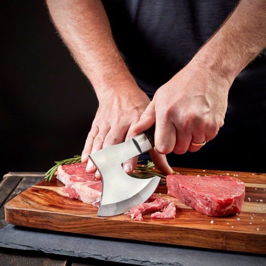 Man using The Choppa axe to cut steak on cutting board