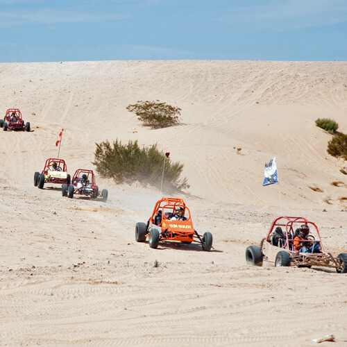 People racing dune buggies in the desert