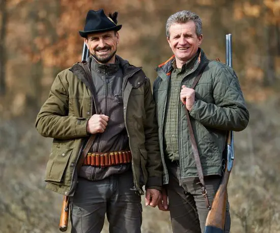 Happy shot of two men in the forest hunting