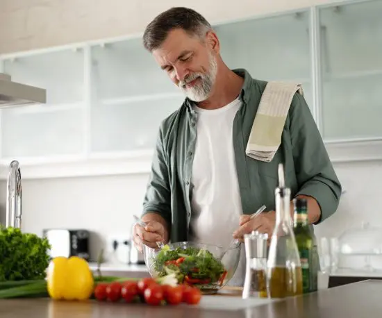 Image of a Happy 60 Year Old Man Preparing Food in the Kitchen
