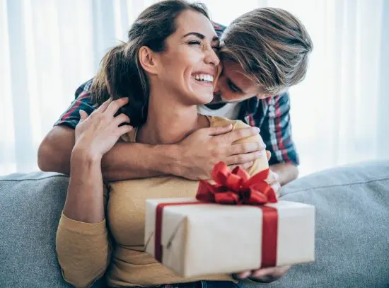 Guy hugging and giving woman a present