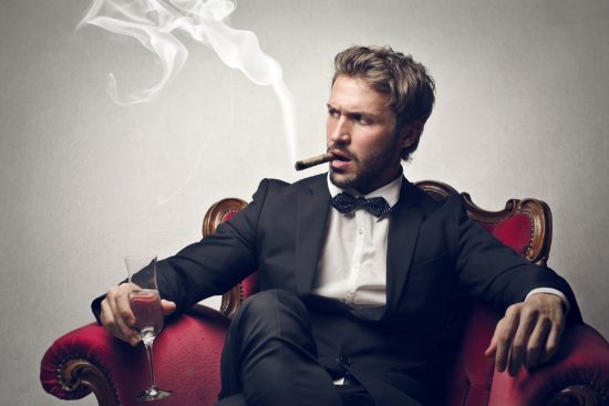 Handsome man in suit sitting on chair smoking a cigar