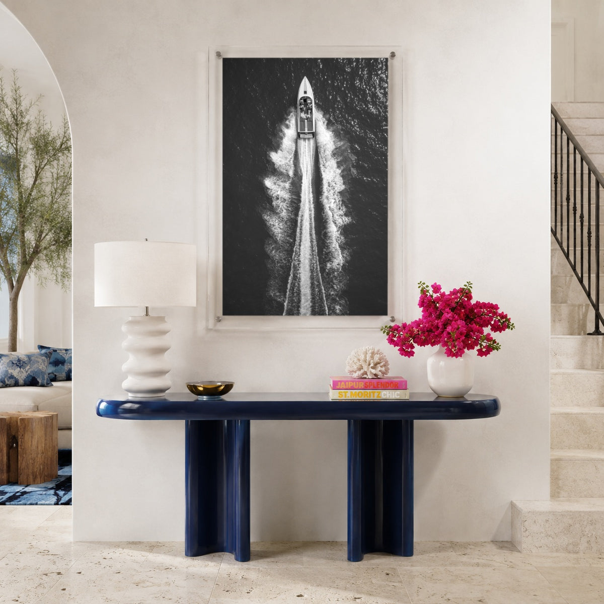 Exit By Sea wall art above a navy console table in a foyer space with stairways aside