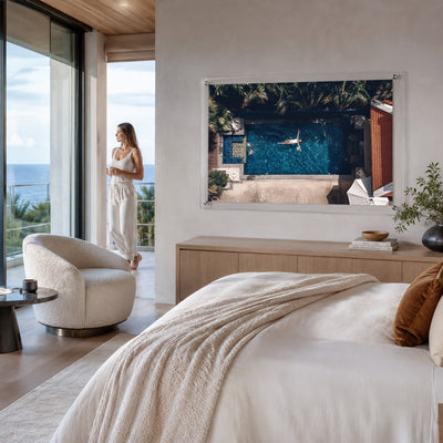 Lap of Luxury wall art displayed above a bed in a bright coastal room with woman looking afar