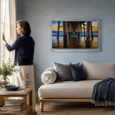 Pier Pressure acrylic wall art displayed above a modern living room sofa with woman standing