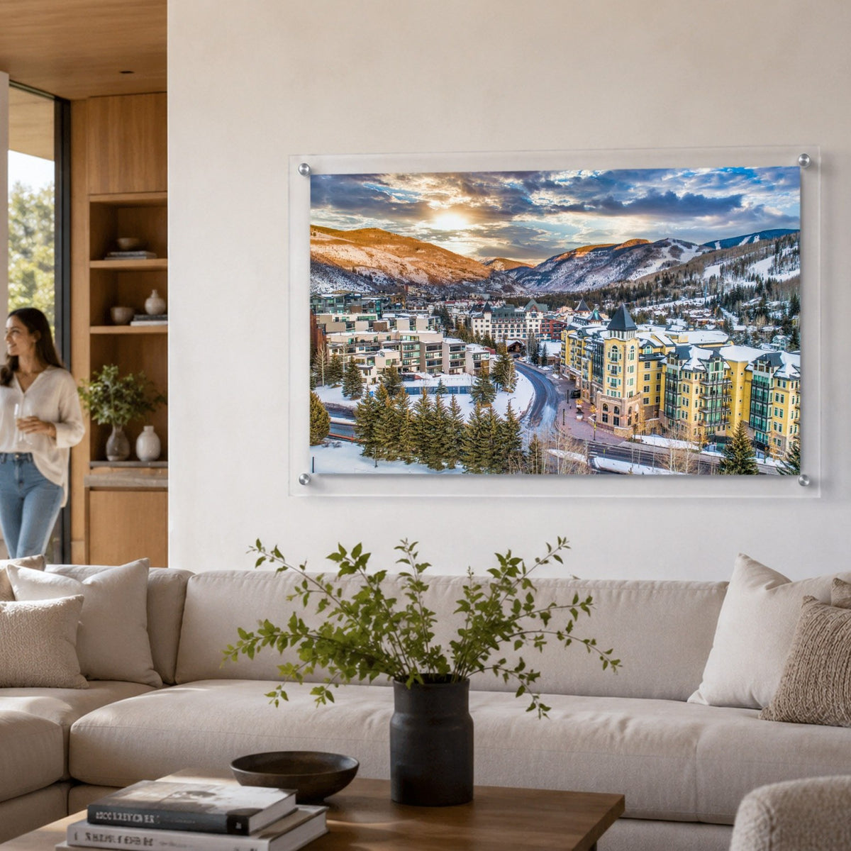 Vail We Meet Again wall art above a bright living room couch with a woman