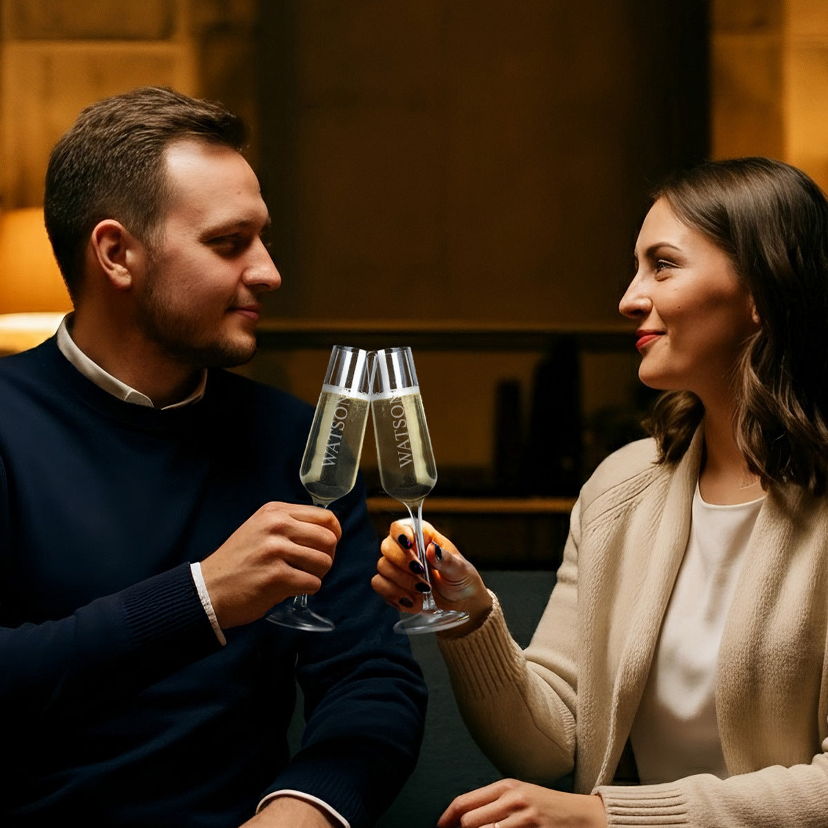 Man and woman holding champagne glasses in a cozy indoor setting