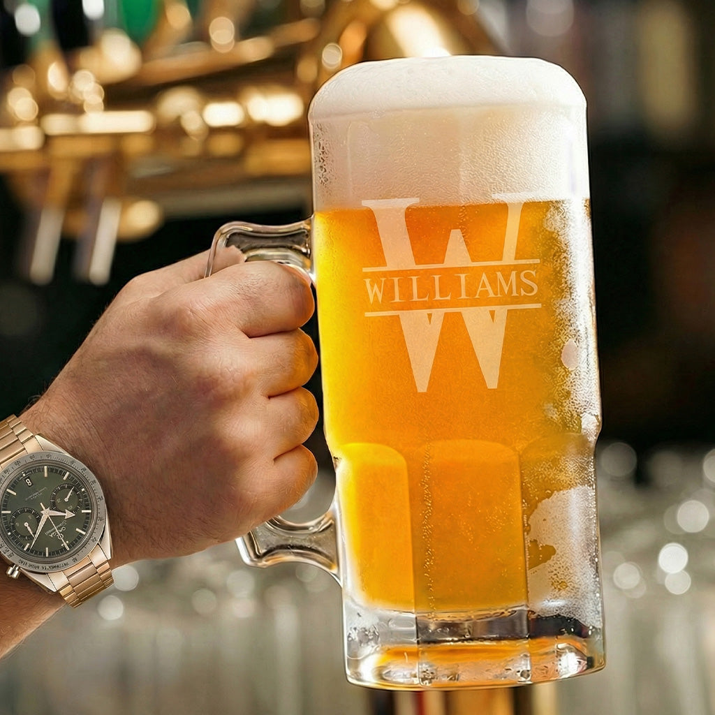 Hand holding frothy beer mug with “WILLIAMS” logo, in a bar setting; wristwatch visible.