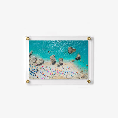 Bright seaside acrylic wall art with a rocky shoreline and beach umbrellas