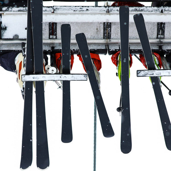 Upward view of ski lift passengers with skis 