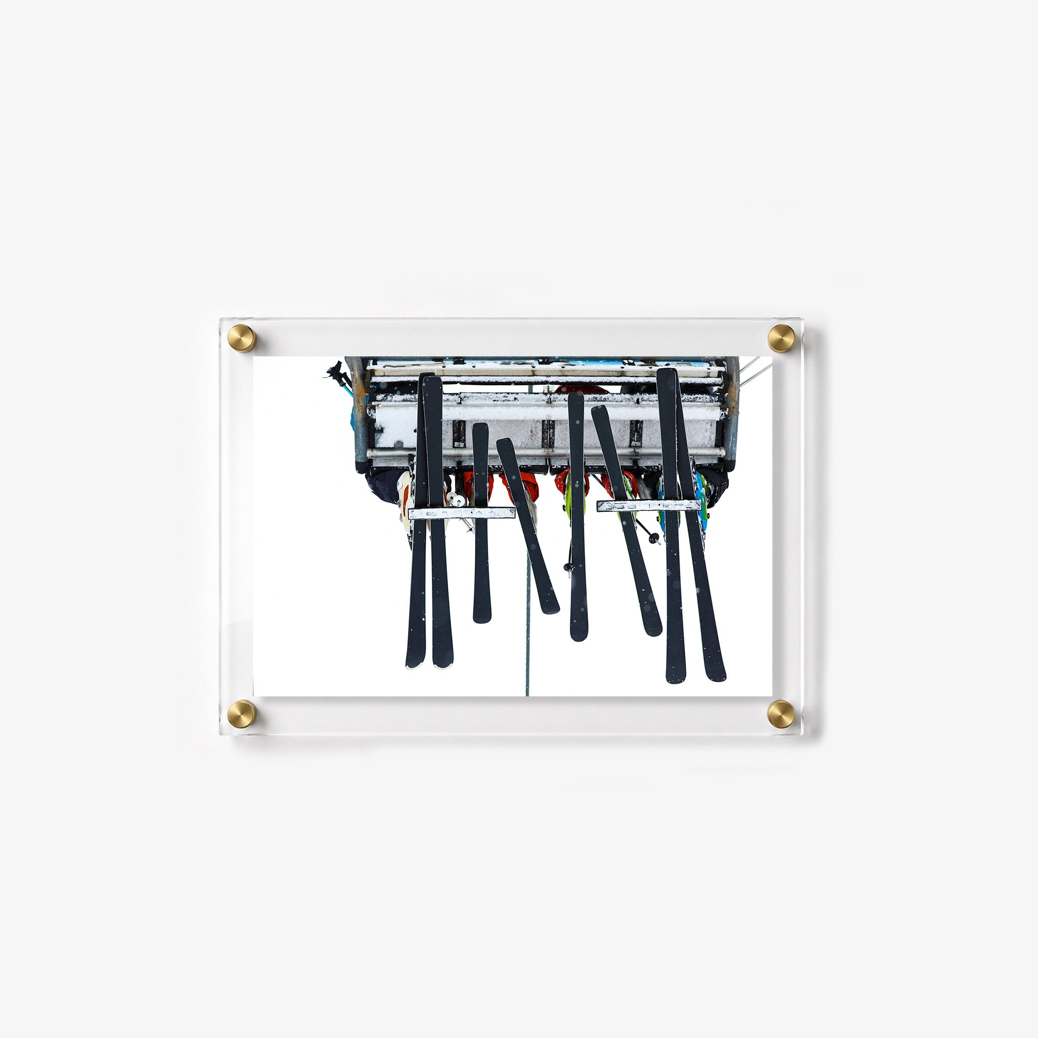 Chairlift scene with skiers, ski poles, and dark skis viewed from below