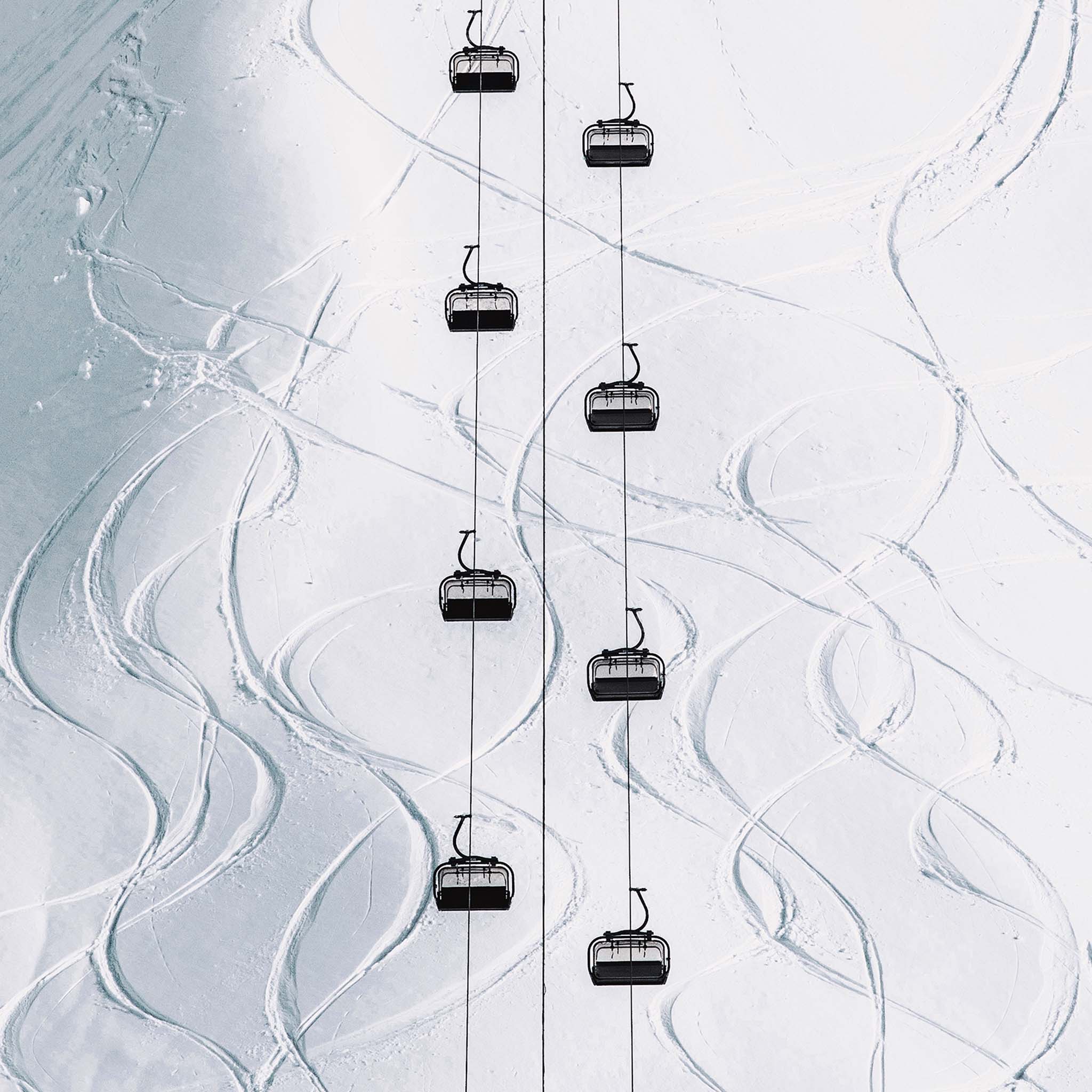Aerial winter scene showing gondola lifts traveling over fresh snow 