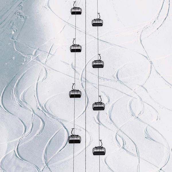 Aerial winter scene showing gondola lifts traveling over fresh snow 